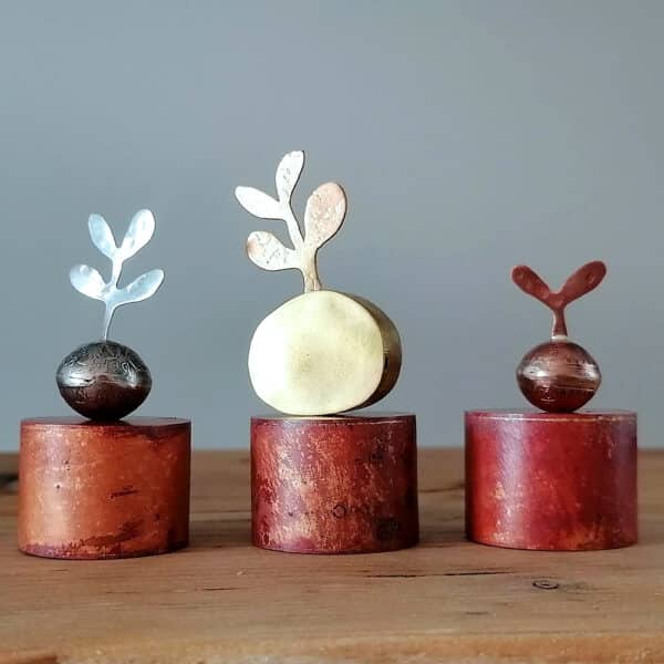 3 metal sculptures of plant standing on their plinths