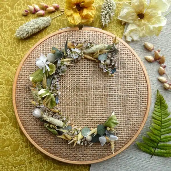 An embroidery hoop covered with hessian with the letter E formed from woven dried flowers