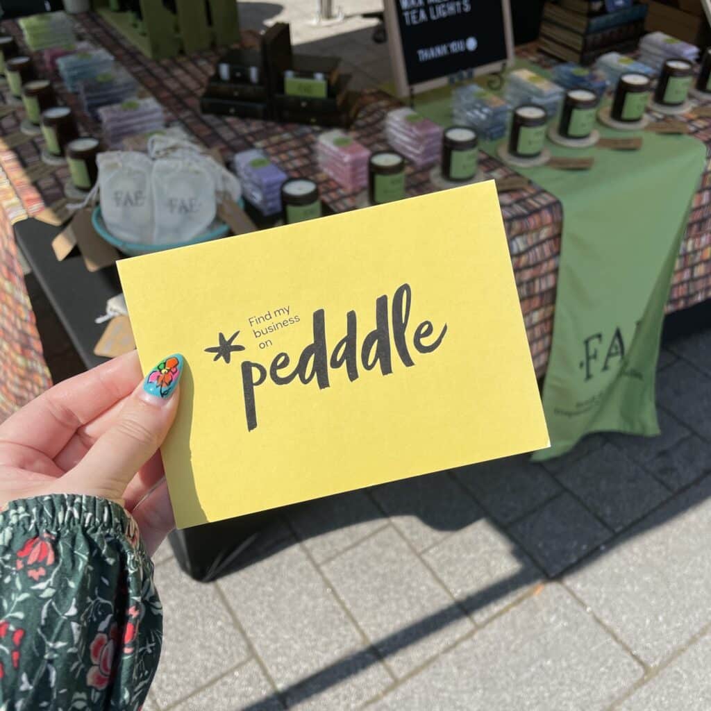 A Pedddle board being held up in front of a Fae Candle Co. stall. successful Pedddle stallholders.
