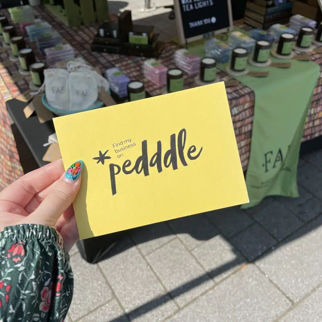 A Pedddle board being held up in front of a Fae Candle Co. stall. successful Pedddle stallholders.