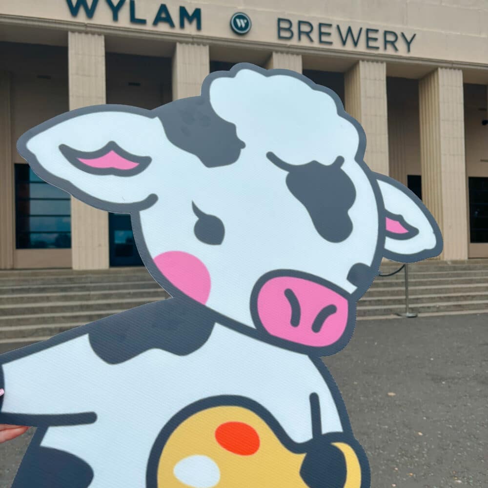 A cartoony artist cow cutout being held infront of the venue, Wylam brewery