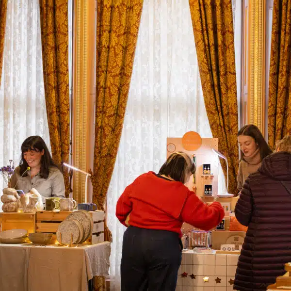 Two female stallholders sell to three female customers as they browse their stalls.