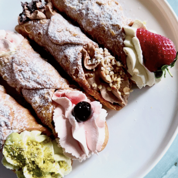 Four sweet cannoli filled with pistachio, blueberry, coffee and finally strawberry cream