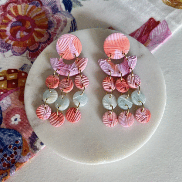 A pair of dangly earrings in sorbet pink and green colours made into discs
