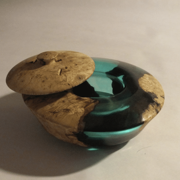 A round wooden bowl and lid with a green resin detail