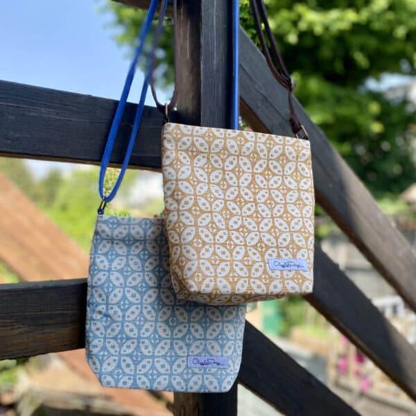 ClogglesDesign - Crossbody Bags made from repurposed fabrics. 23cm x 23cm x 8cm D. Orange fabric with abstract white flower pattern. Blue fabric with abstract white flower pattern. Faux suede leather straps.
