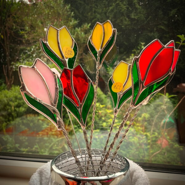 A bunch of stained glass tulips in a rose bowl with green leafy background by by Tad Glass