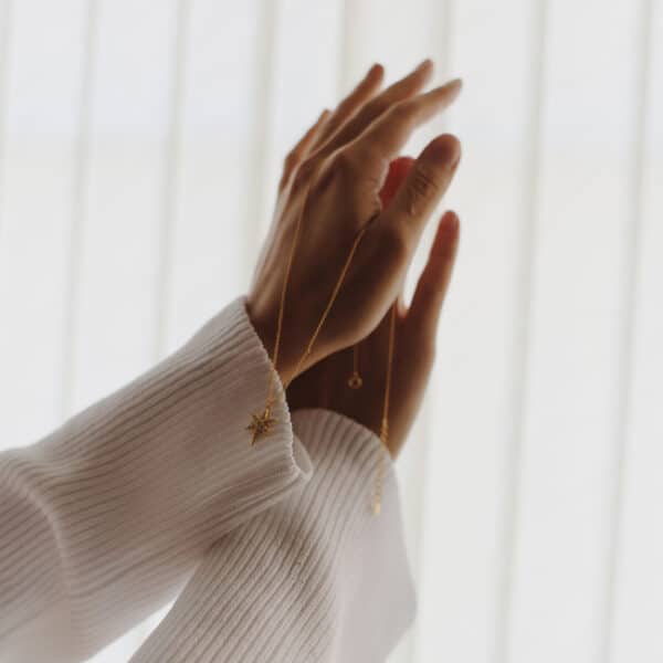 Model holding a gold star necklace