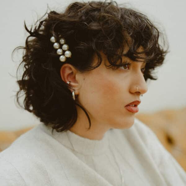 Model wearing cream jumper dress with pearl hair accessories