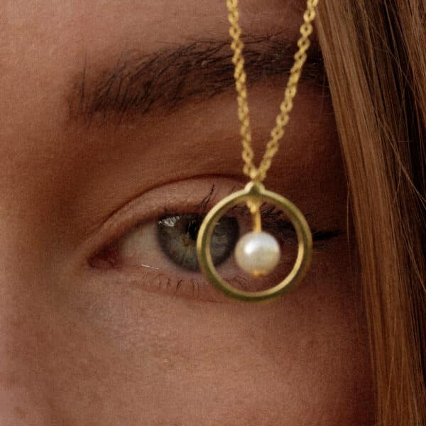 Pearl necklace hanging in front of models eye