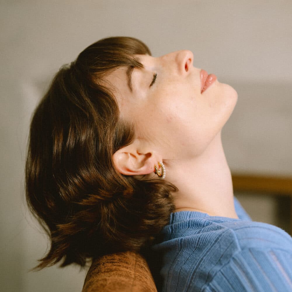 Girl with her head lying back on the sofa showing off an ear stack with short hair