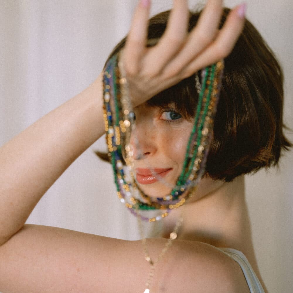 Girl holding a handful of gemstone multicoloured necklaces