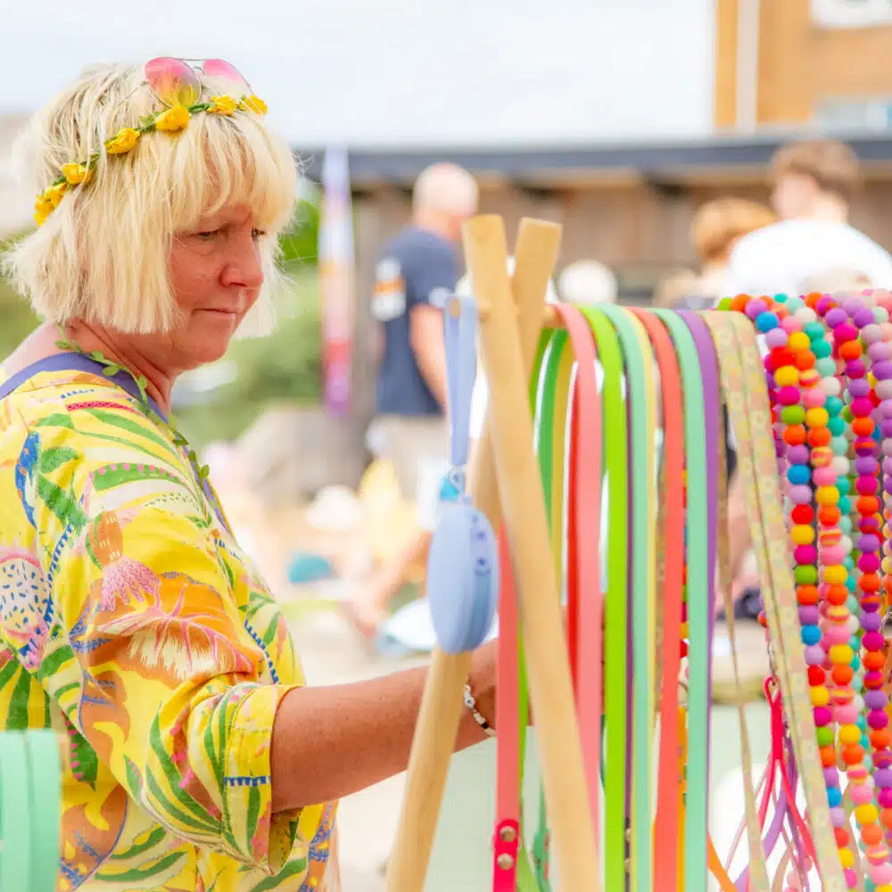 A woman dressed in yellow browsing colourful dog leads at a market