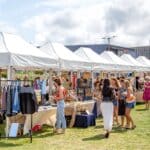 White gazebo market stalls with bright stock on the grass