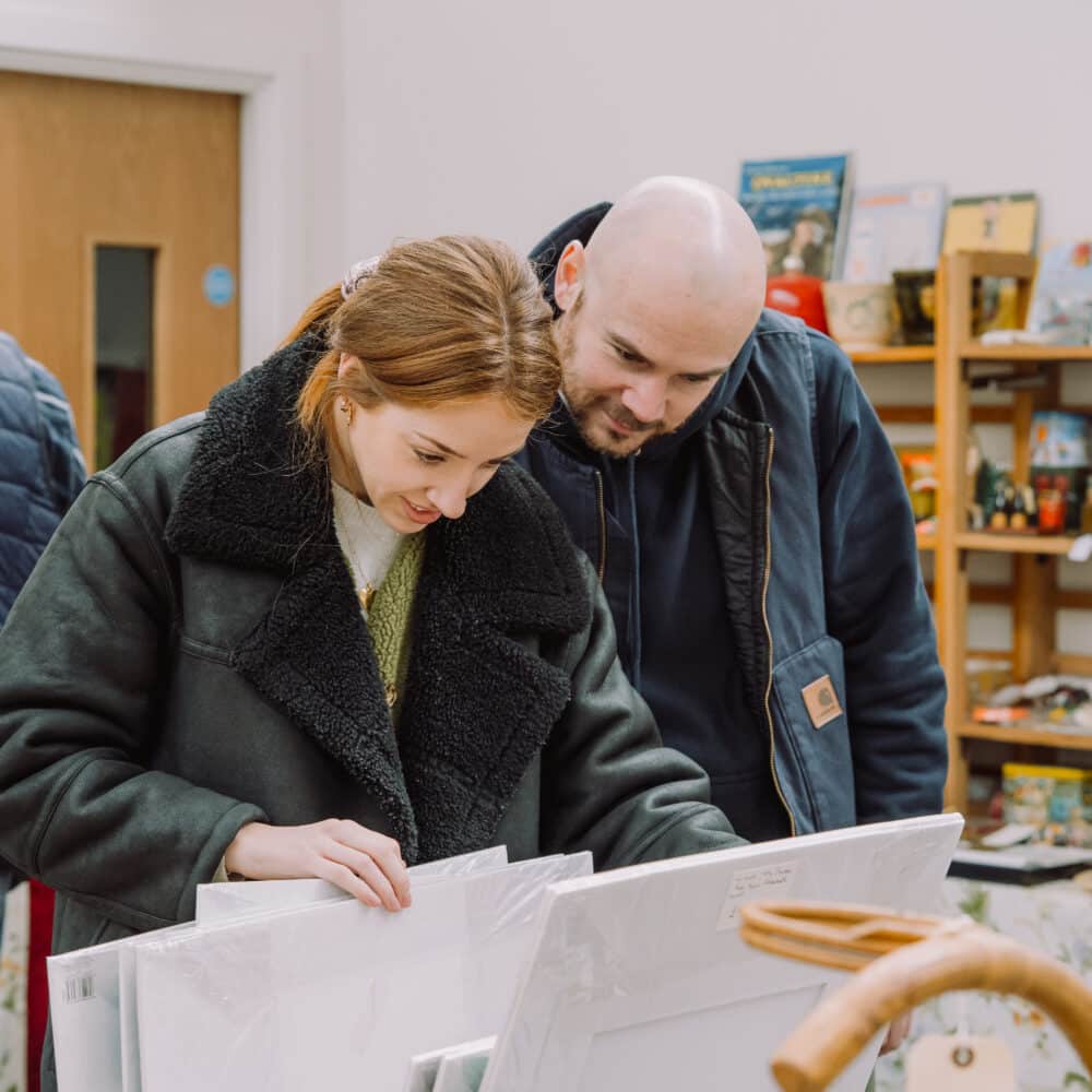 Two customers looking through vintage artwork at a So Retro vintage fair