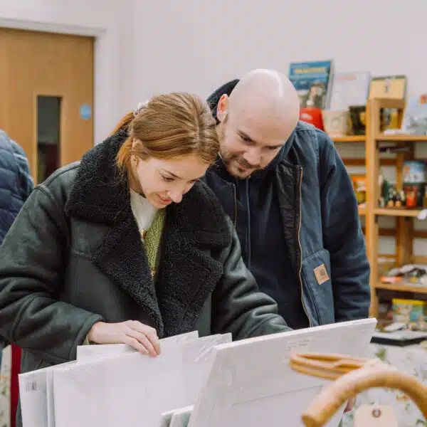 Two customers looking through vintage artwork at a So Retro vintage fair