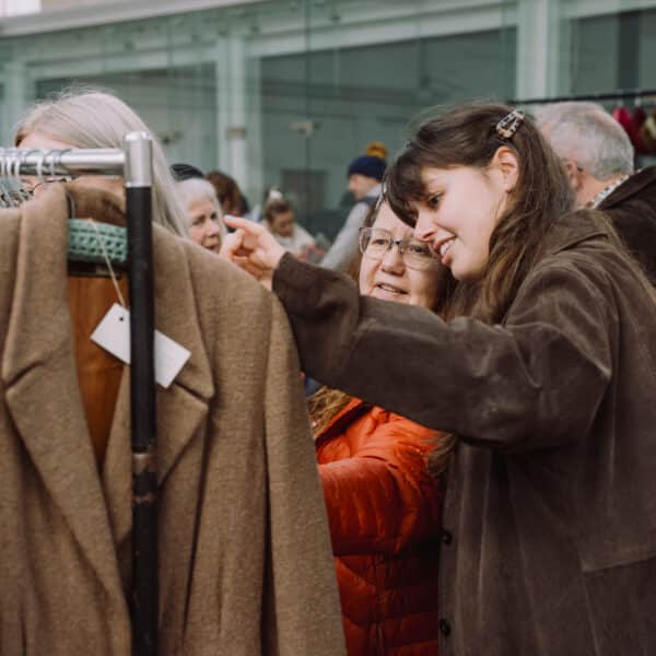 A lady looking through rails of vintage clothing at a So Retro vintage fair