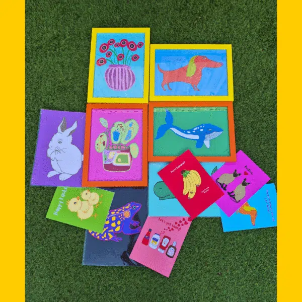 A selection of brightly coloured prints and greetings cards on grass.