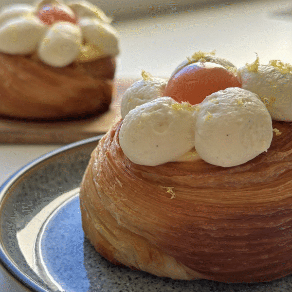 A sweet pastry with cream piping in a flower shape with a mango centre