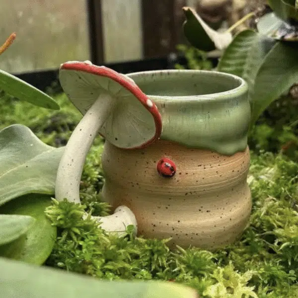 A ceramic mug with a mushroom handle and ladybird decoration