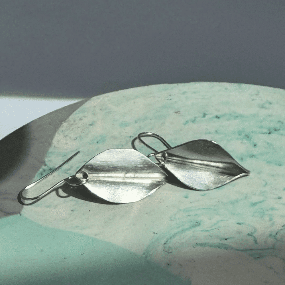 A pair of silver drop earrings with leaf design