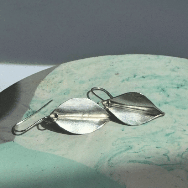 A pair of silver drop earrings with leaf design