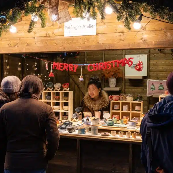Fatfinger Atelier stall at Christmas market displaying handmade ceramic gifts and panda tea sets, with customers browsing