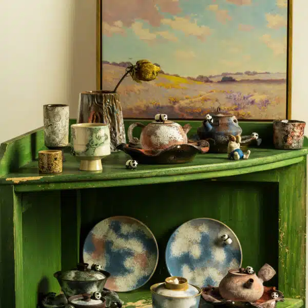 Handmade panda ceramic tea sets and cups displayed on a green wooden shelf, featuring sponge-painted glaze and unique textures, by Fatfinger Atelier
