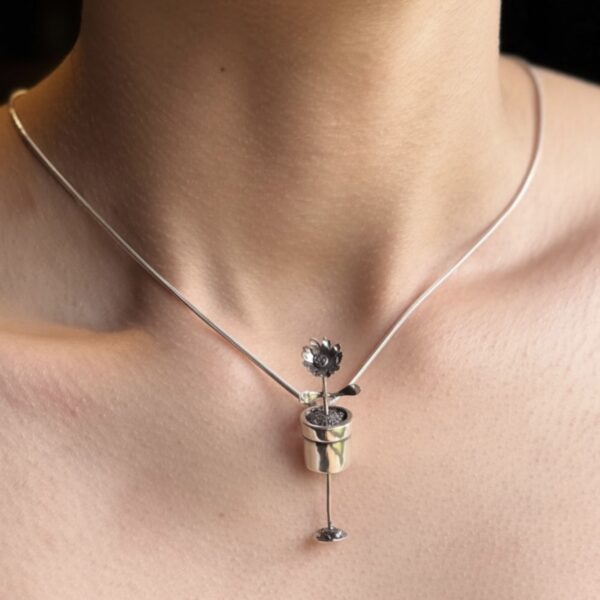 A flower in a pot necklace made from silver. It moves up and down in its pot. Hence the ‘Grow with me’ name. I’m a model.