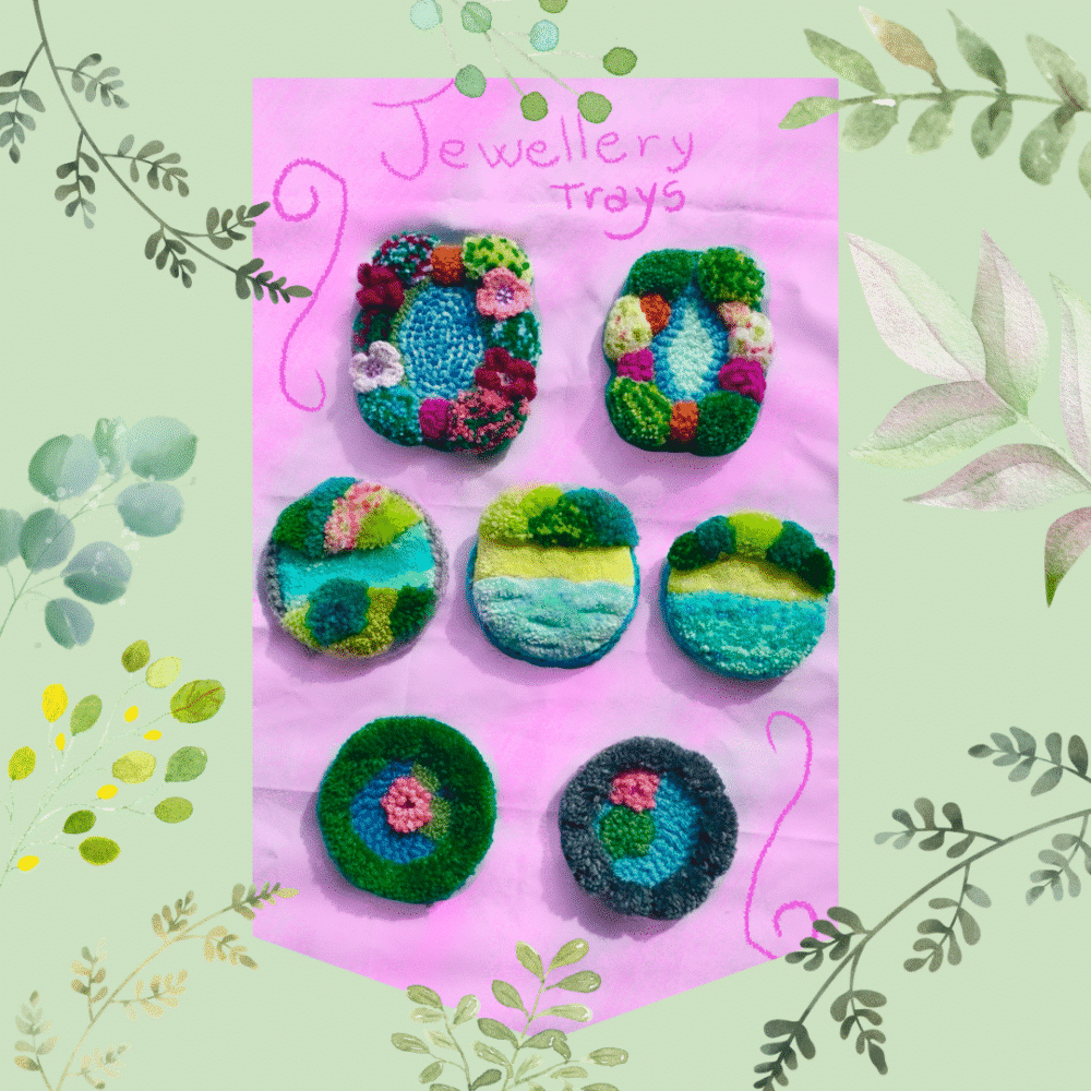 A square flat lay photograph framed by a sage green border of delicate watercolour leaves and vines. At the centre, set against a pink background under the hand-drawn text "Jewellery Trays", are seven highly textured, colourful punch needle and tufted textile dishes. The collection features two oval trays with raised floral borders, three circular trays depicting abstract green and blue landscape designs, and two smaller round trays resembling mossy ponds with a pink blossom at the centre.