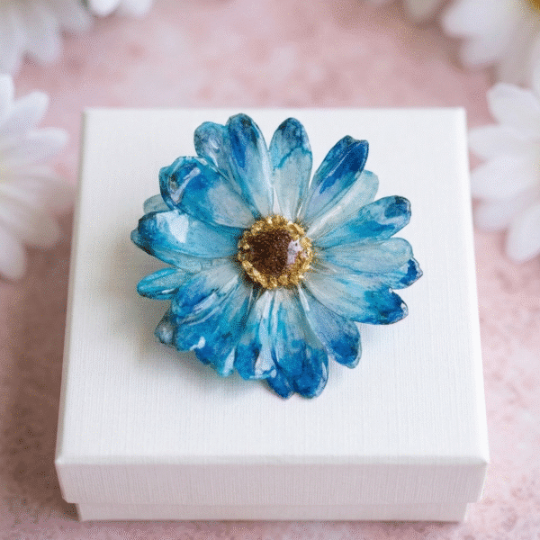 Handcrafted blue preserved daisy brooch in a white gift box by Joie Creations, Canterbury.