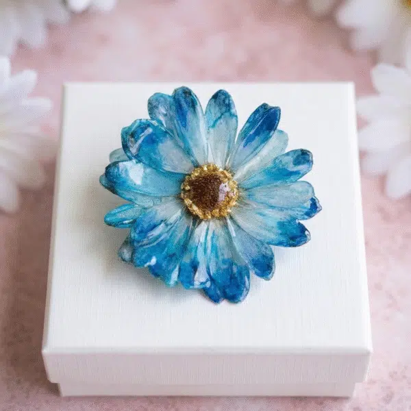 Handcrafted blue preserved daisy brooch in a white gift box by Joie Creations, Canterbury.