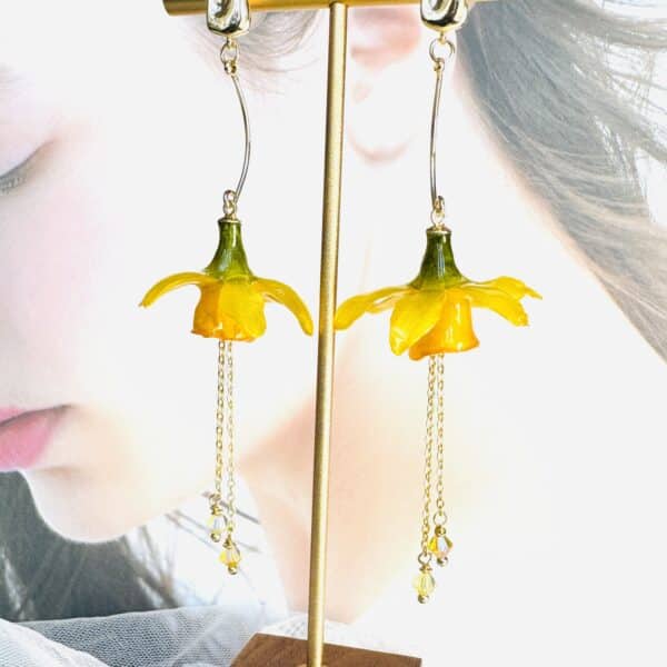 Handcrafted real yellow daffodil resin earrings on a gold display stand by Joie Creations, Canterbury.