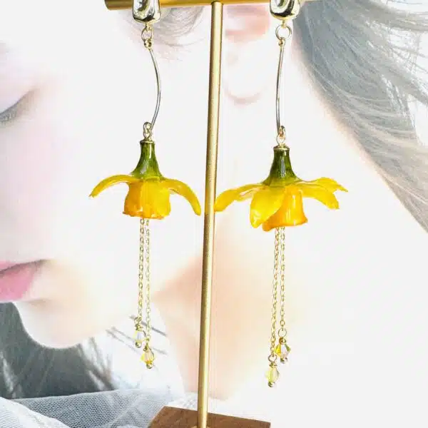 Handcrafted real yellow daffodil resin earrings on a gold display stand by Joie Creations, Canterbury.