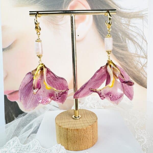 Handcrafted real purple orchid earrings preserved in resin on a display stand by Joie Creations, Canterbury.