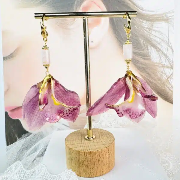 Handcrafted real purple orchid earrings preserved in resin on a display stand by Joie Creations, Canterbury.