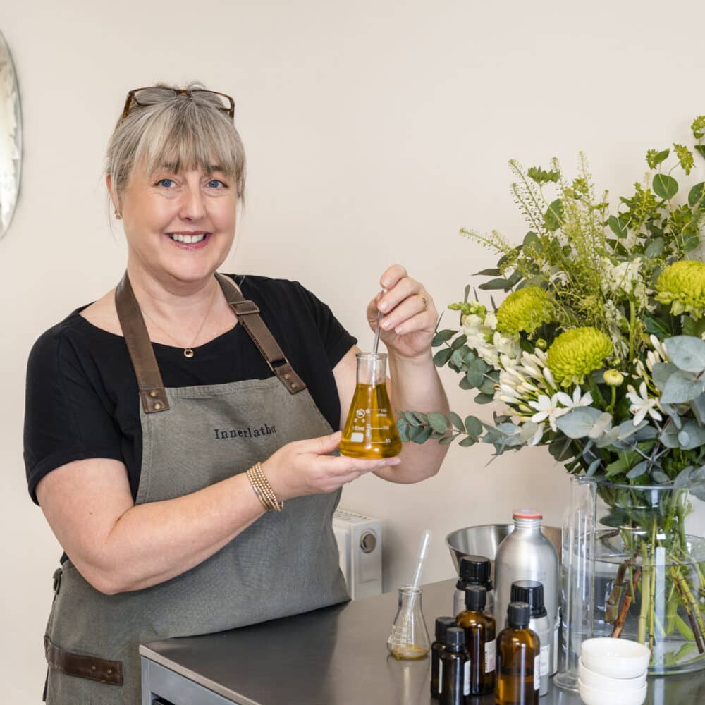Innerlather: Nicci Trudgeon from Innerlather, holding a glass flask and pipette, making Nourish and Glow Skin Oil