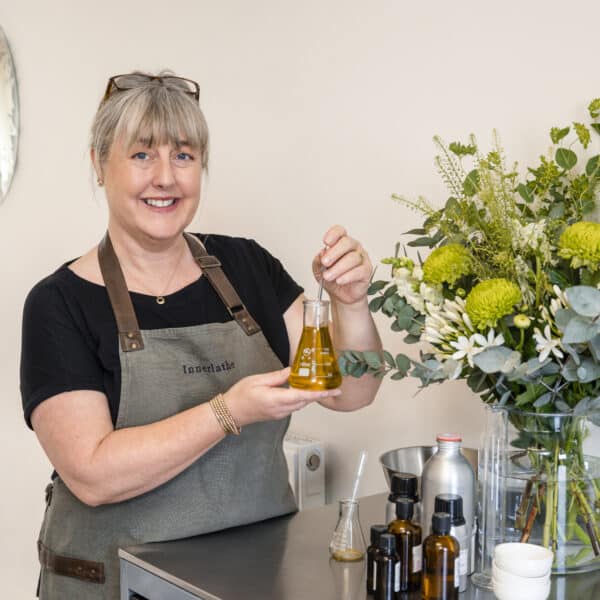 Innerlather: Nicci Trudgeon from Innerlather, holding a glass flask and pipette, making Nourish and Glow Skin Oil