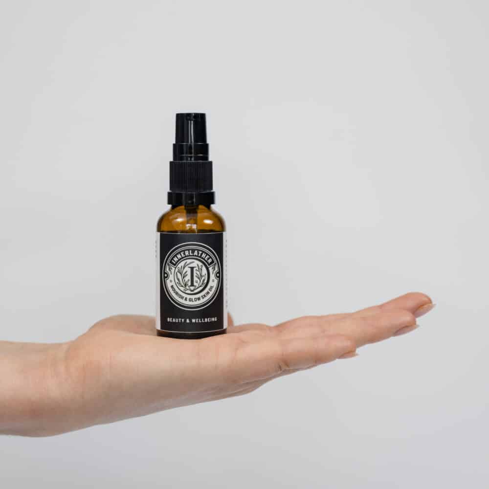 A hand holding a little brown glass bottle of Nourish & Glow Skin Oil
