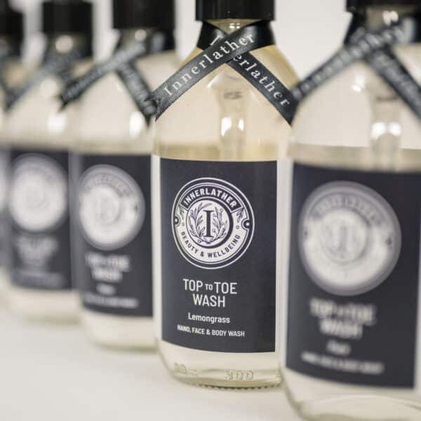 Clear glass bottles of Innerlather Top to Toe Aromatherapy wash.
