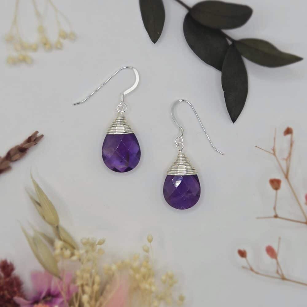A pair of earrings which feature faceted amethyst teardrop beads which are wrapped in silver-tone wire by SunstoneAndFern
