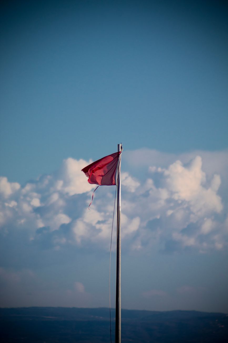 red flag fluttering against a cloudy sky in grado